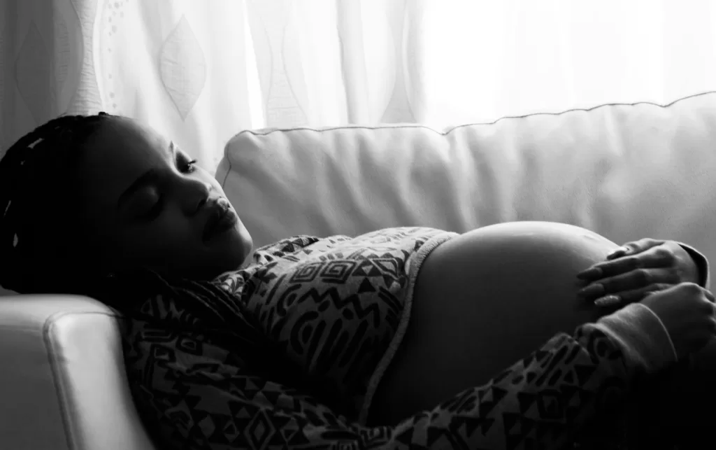 black and white photo of pregnant woman laying on couch